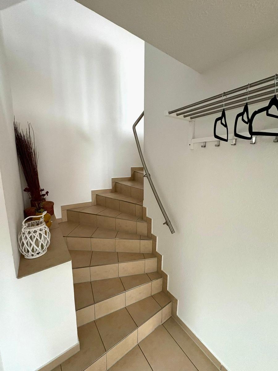 Treppe mit Metallgeländer und Kleiderständer an der Wand.