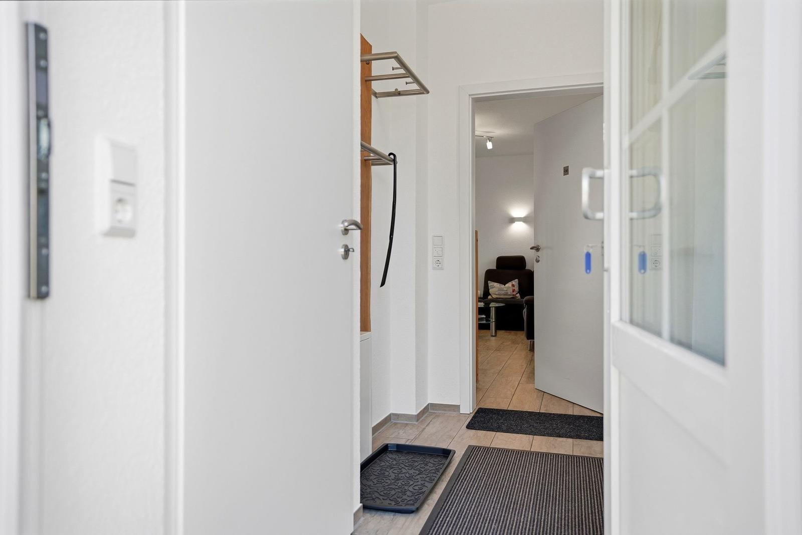 Eingangsbereich mit Tür, Teppich und Sicht in Wohnzimmer.