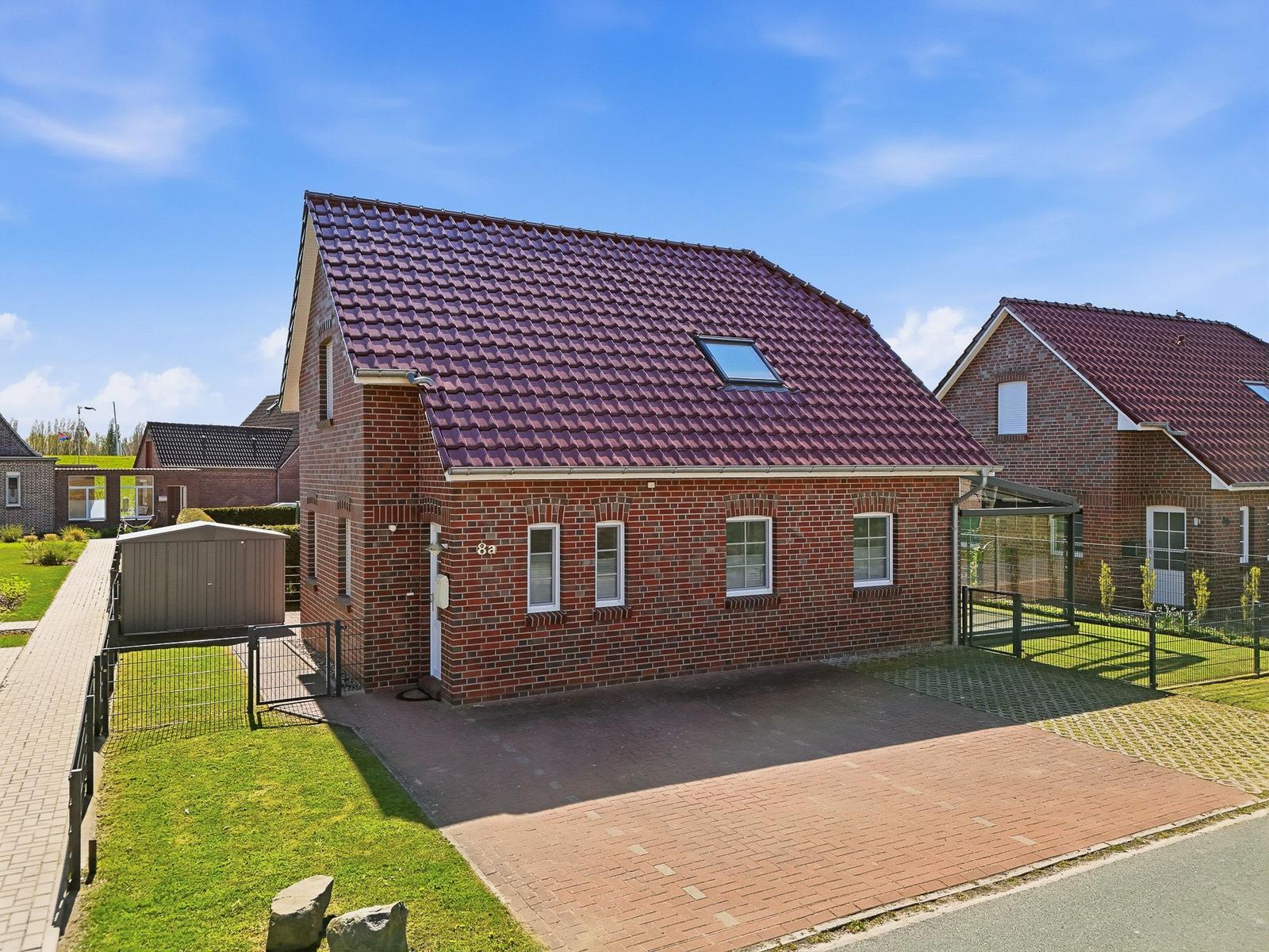 Ein zweistöckiges Haus mit rotem Ziegeldach und Garten. Vor dem Haus befindet sich eine Garage.