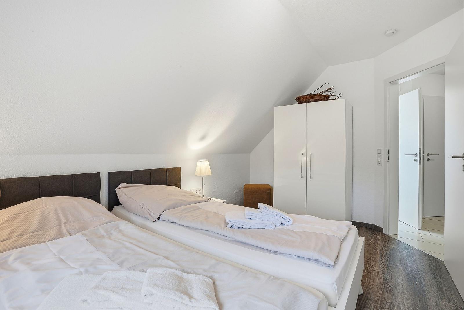 Room with double bed, wardrobe, and nightstand under sloped ceiling