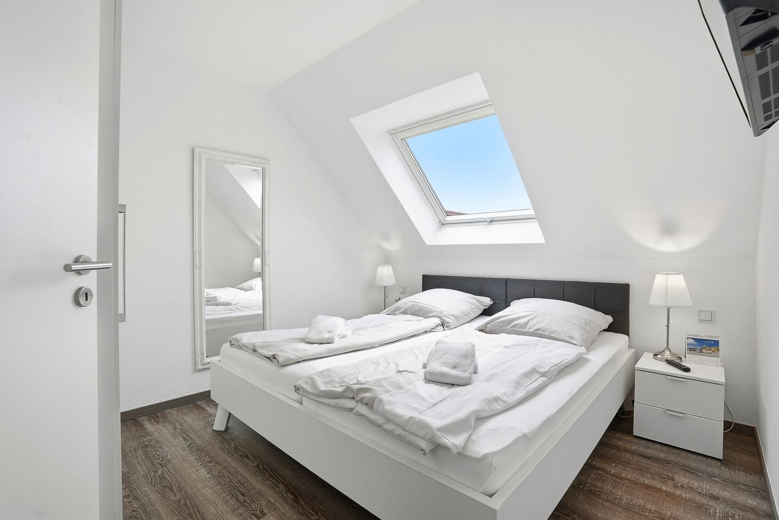 Bedroom with sloped ceiling, double bed, and skylight.