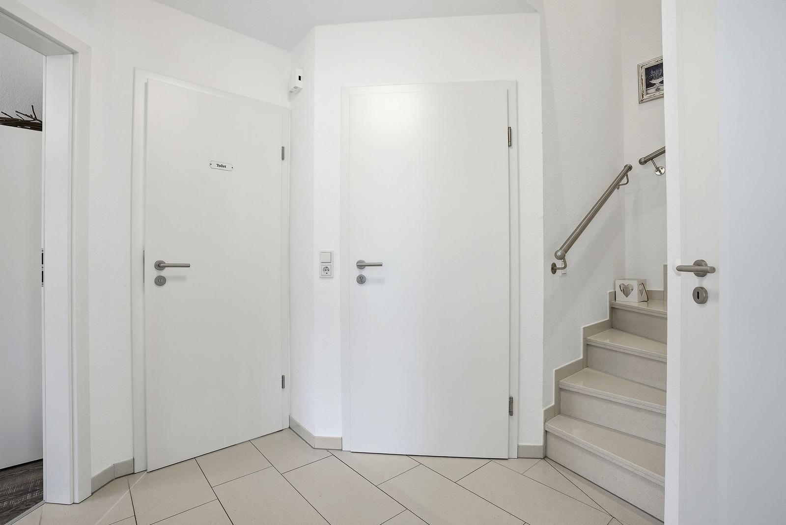 Hallway with two doors and staircase to upper floor.