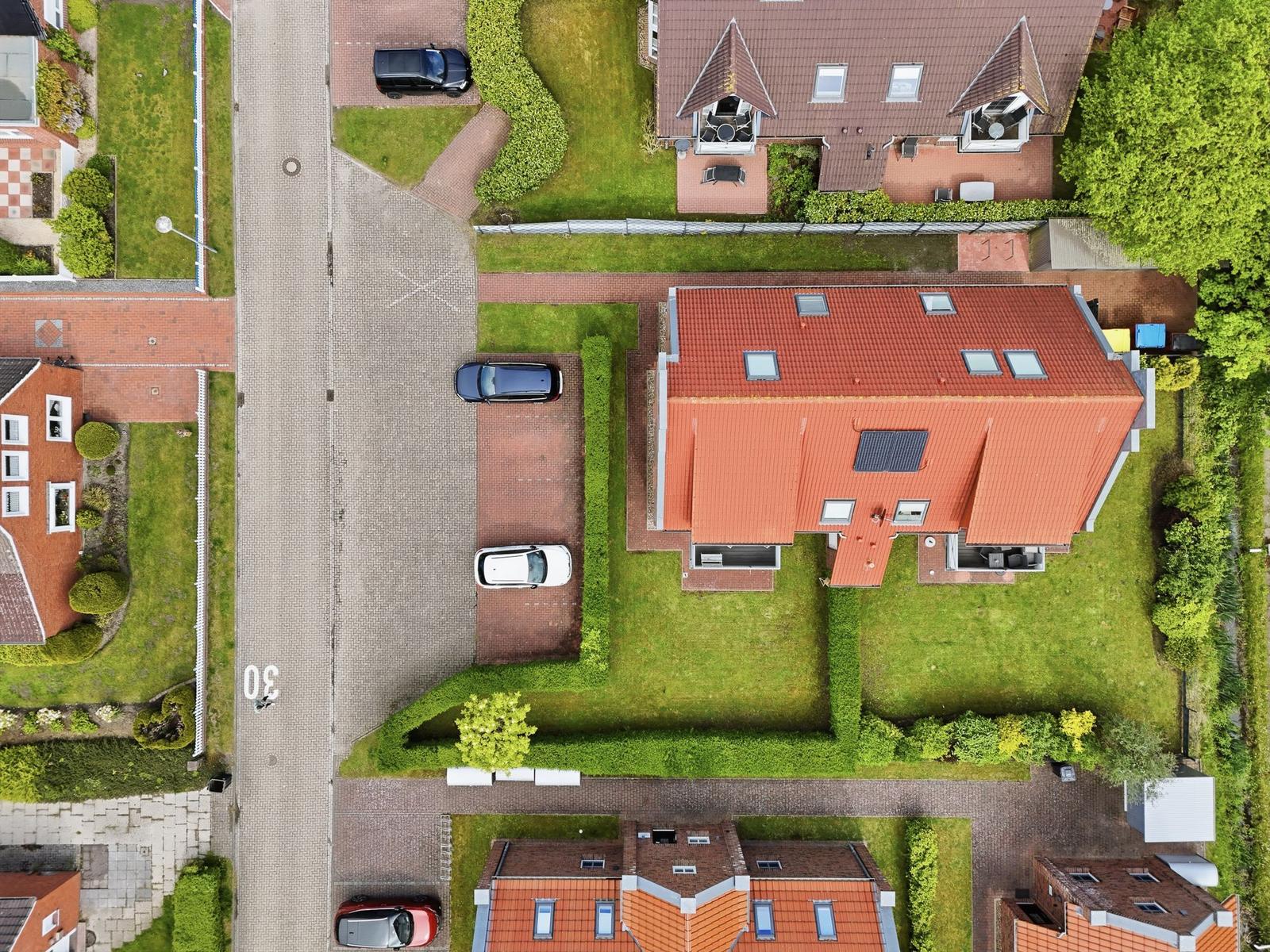 House with red roof, paved yard, and green lawn area.