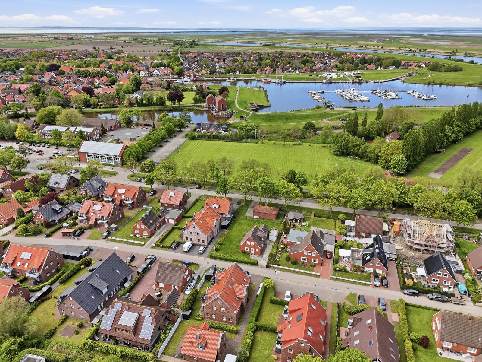 Aerial view of a residential area with houses, green spaces, and a harbor with boats.