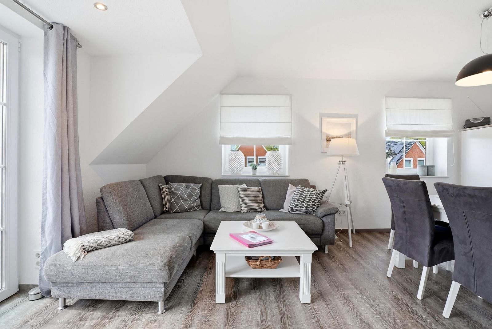 Living room with gray sofa, white coffee table, and dining area.