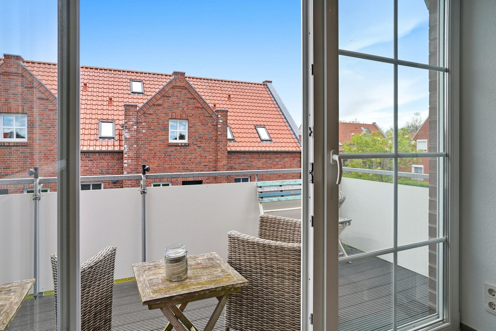 Terrace with table and chairs. View of red roofs and white walls.