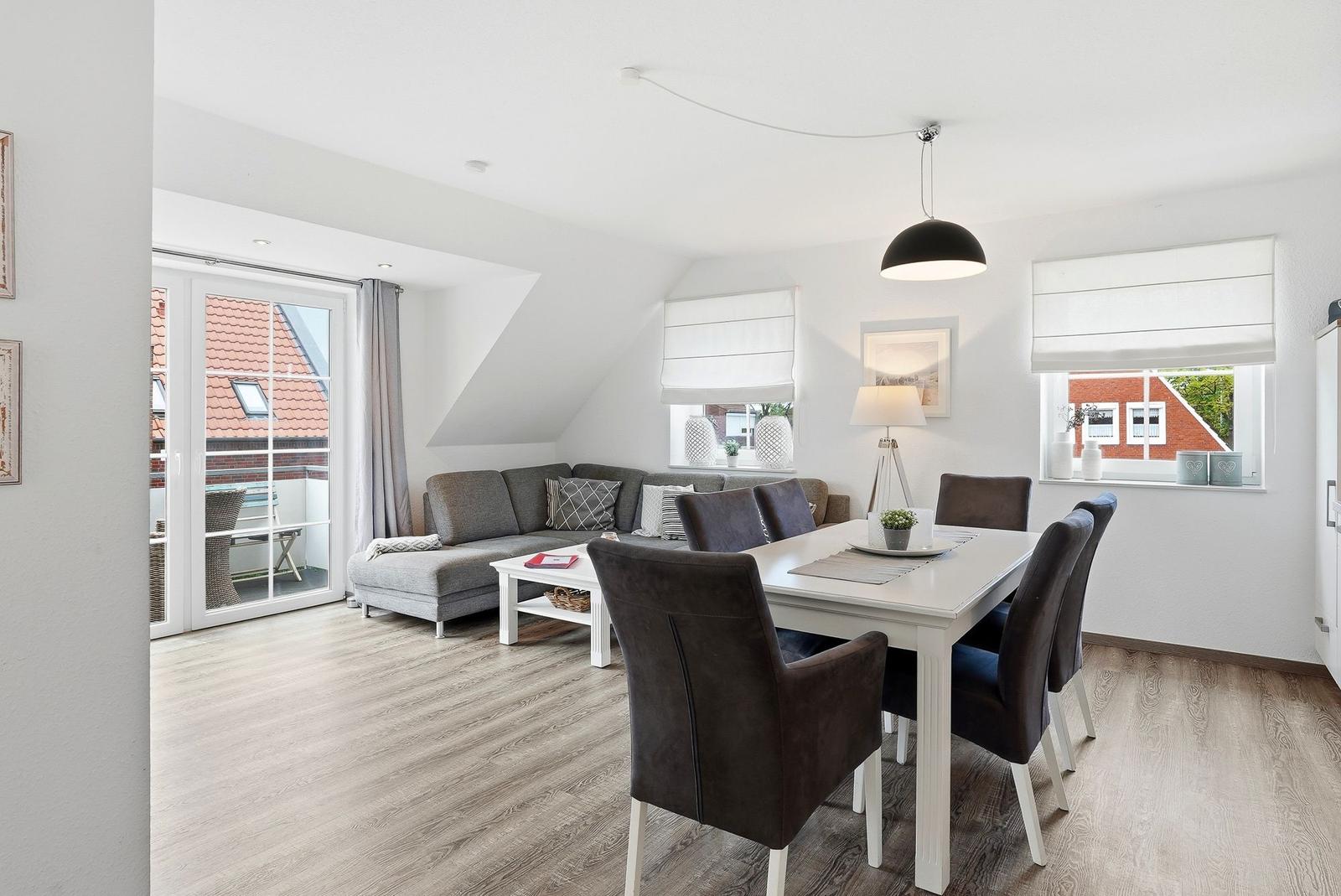 Living and dining area with sofa, dining table, and balcony door.