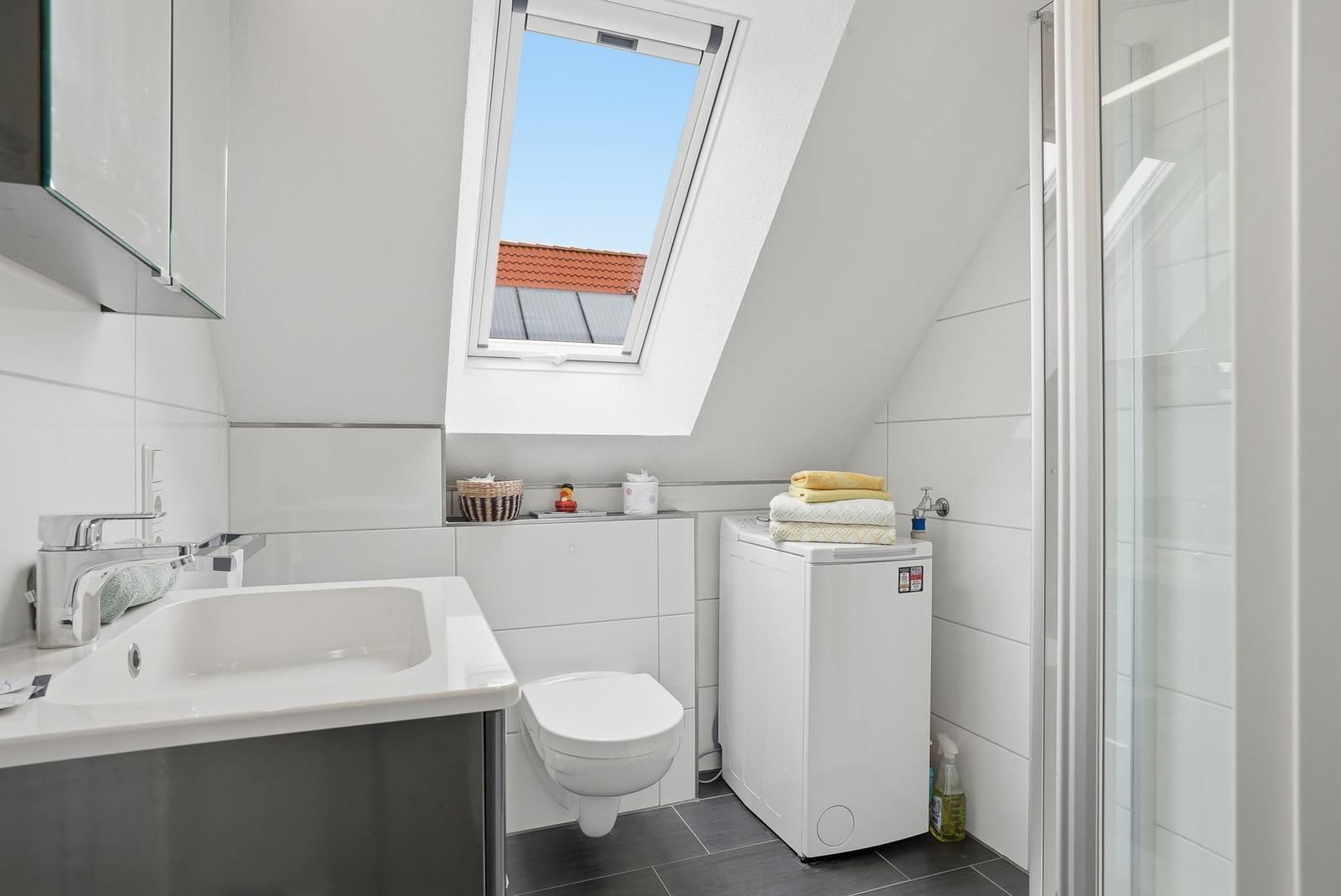 Bathroom with skylight, washing machine, and shower.