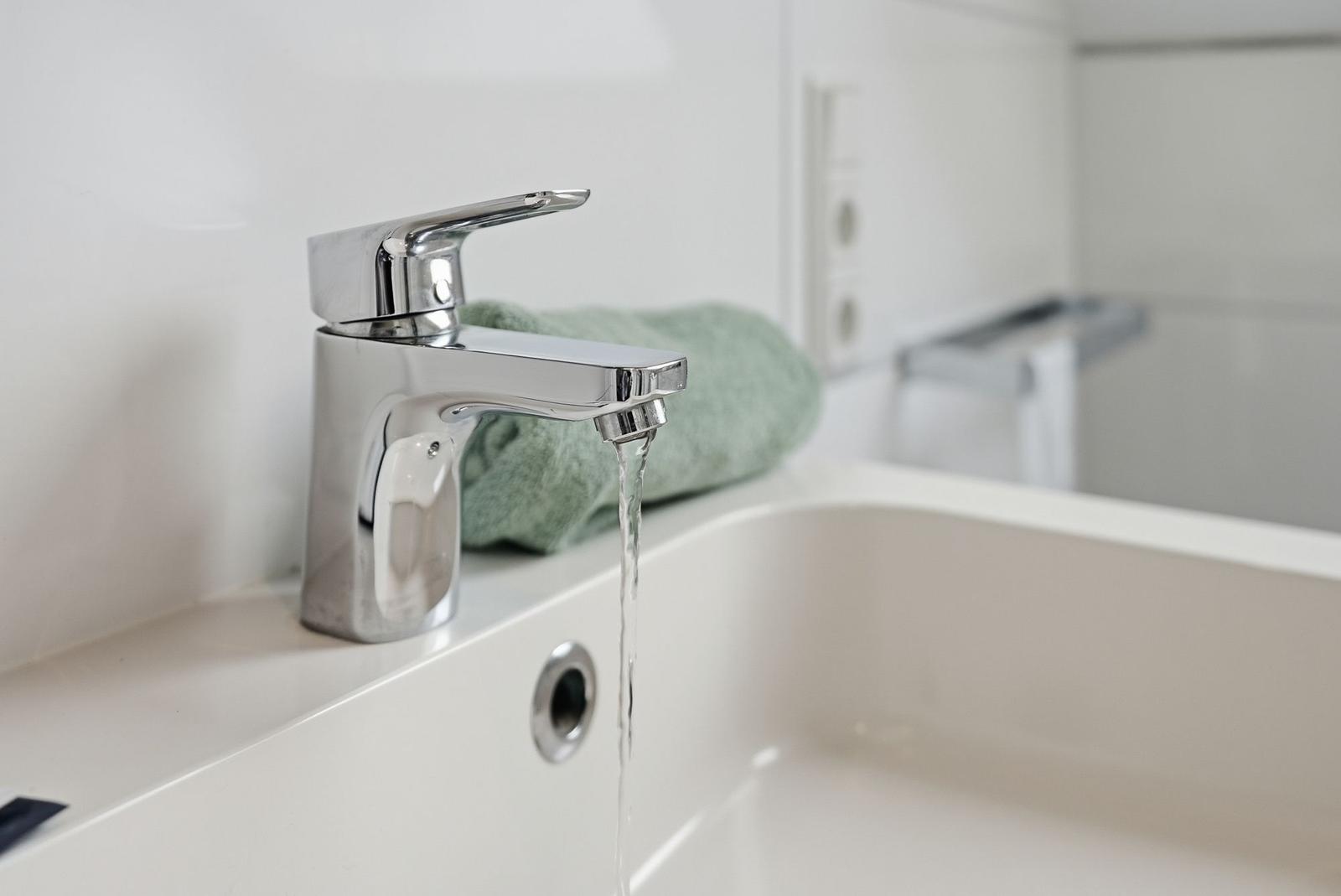 A modern sink with faucet and green towel.