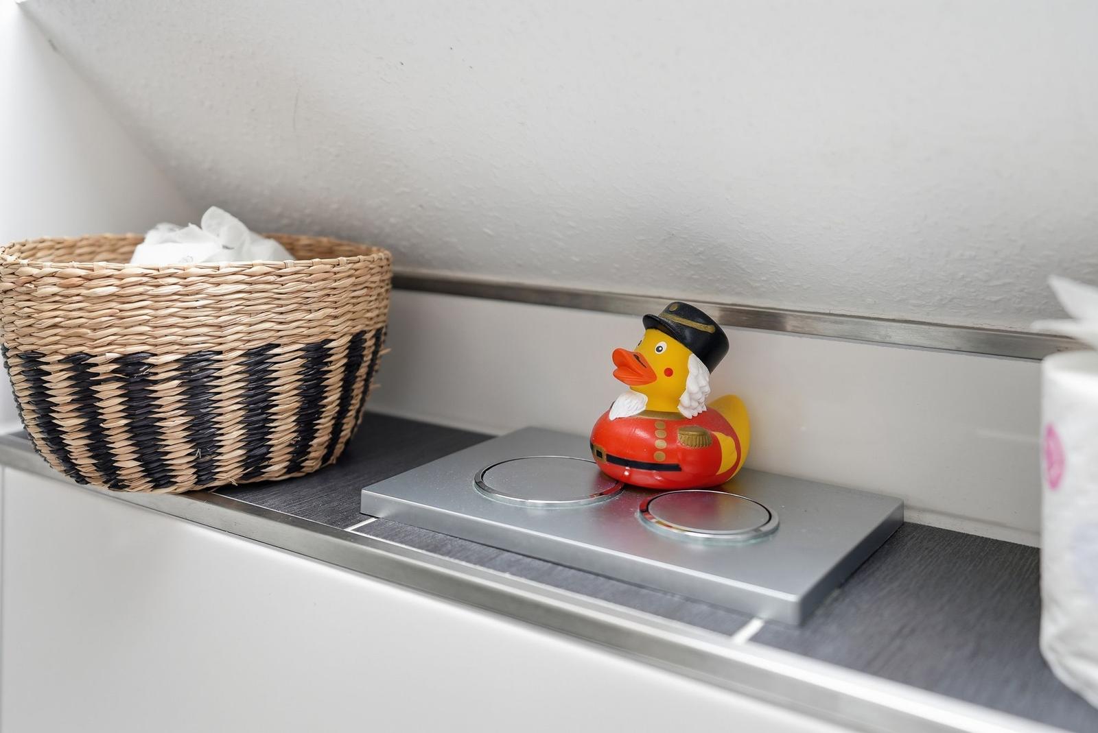 A basket with towels and a duck on a sink edge.