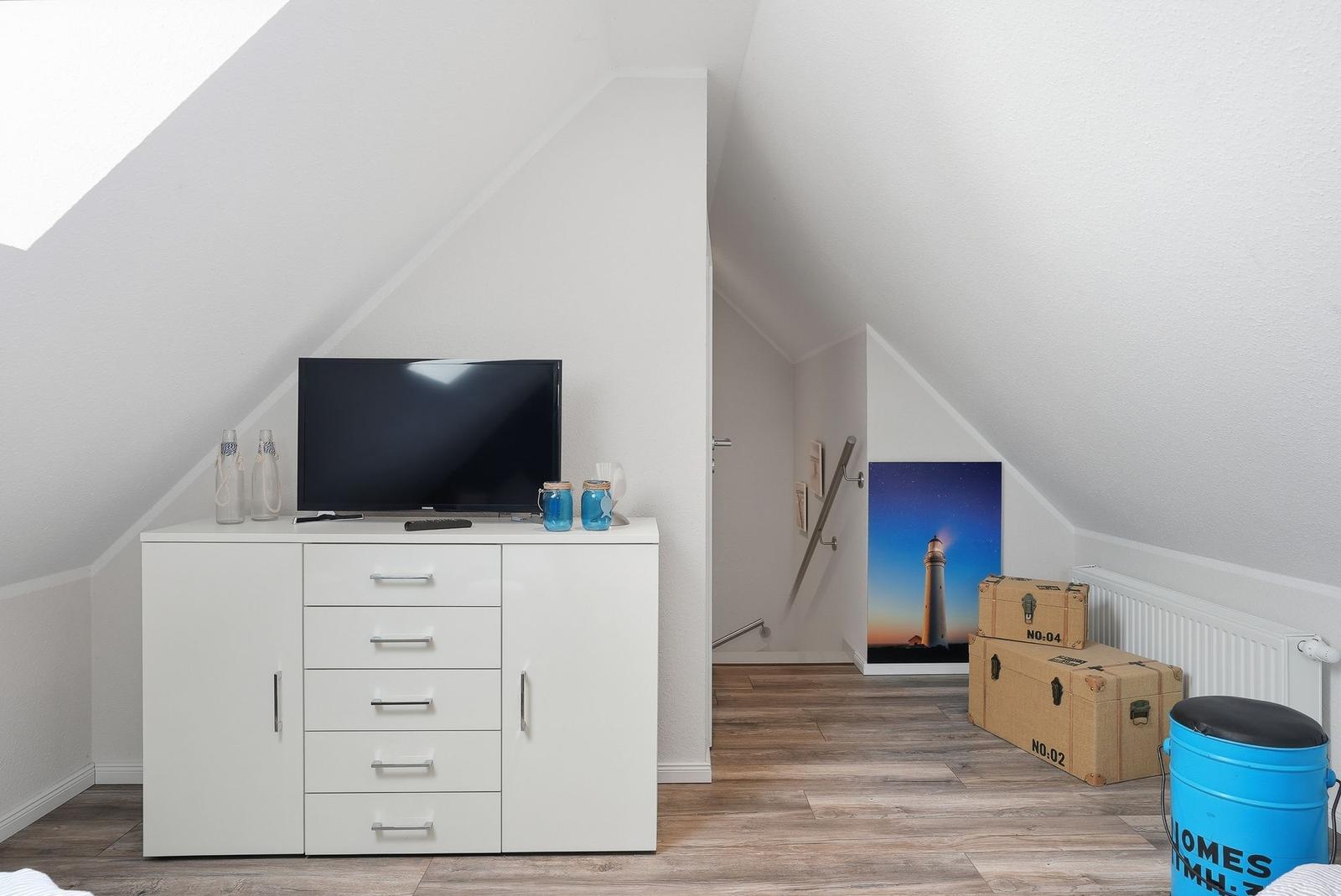 Bedroom with TV, cabinet, and light image on the wall.