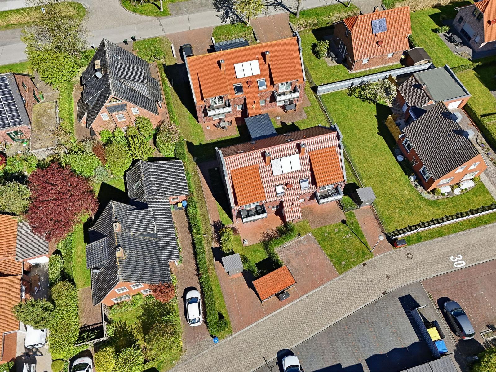 Aerial view of houses with gardens and streets. Some houses have solar panels.