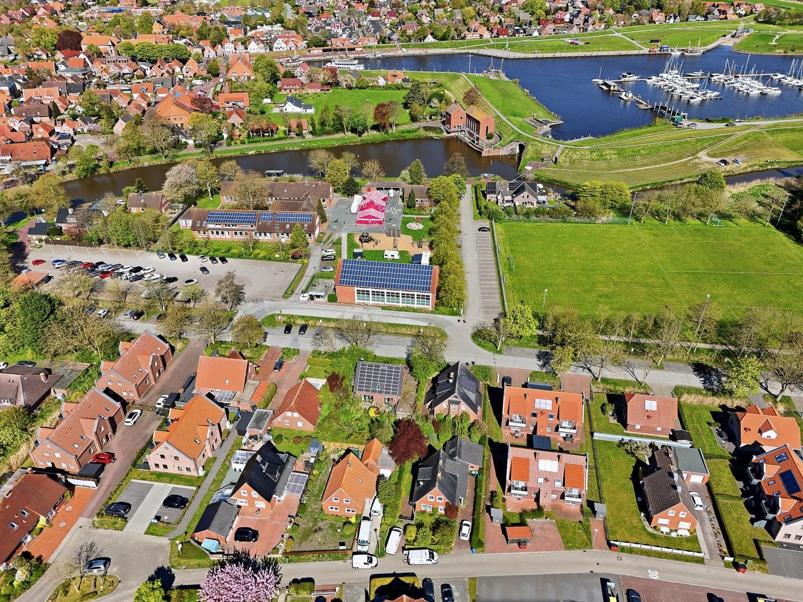Aerial view of houses, a river, and a harbor with boats.