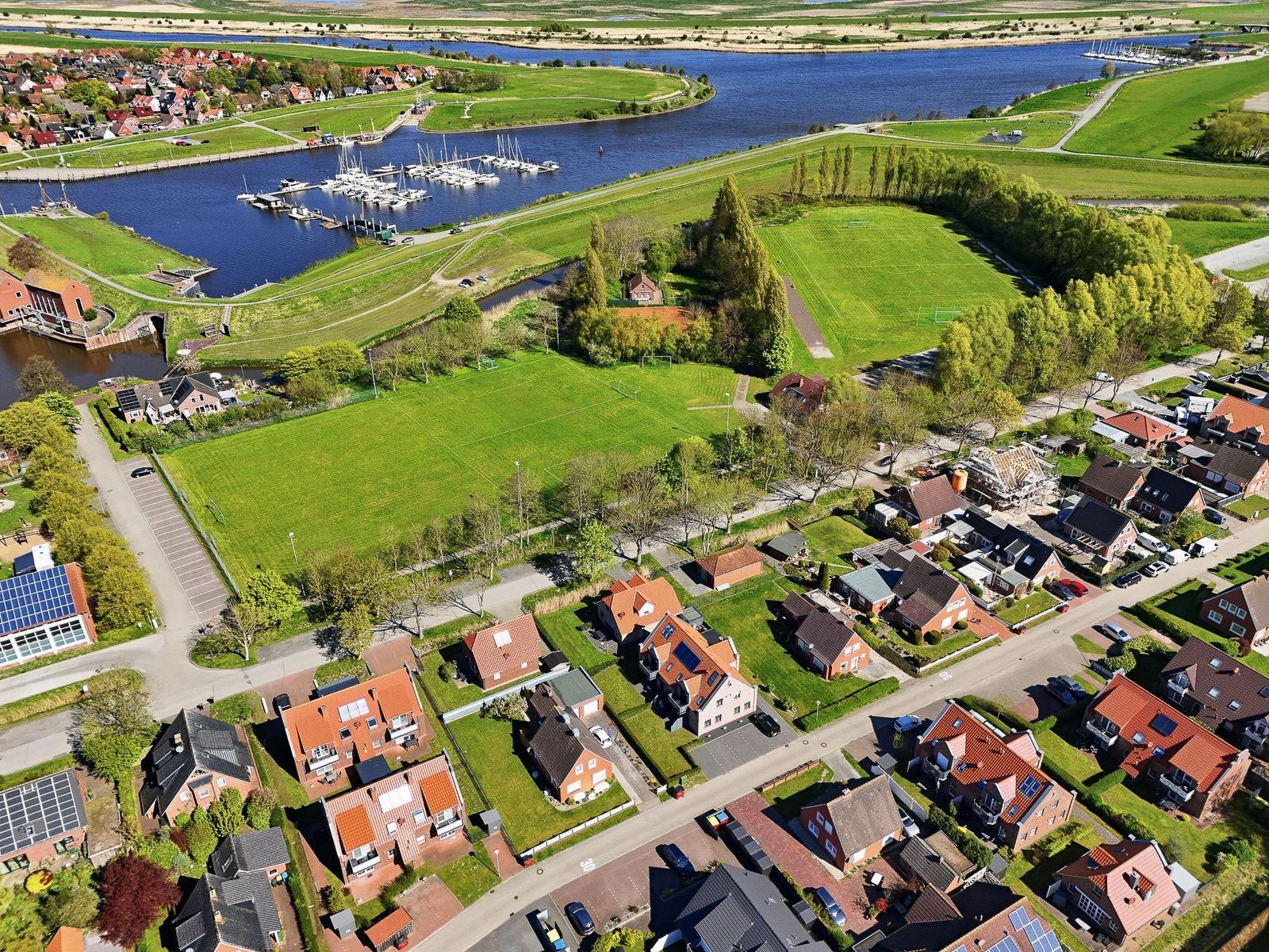 Aerial view of a residential area near a river with marina and sports fields.