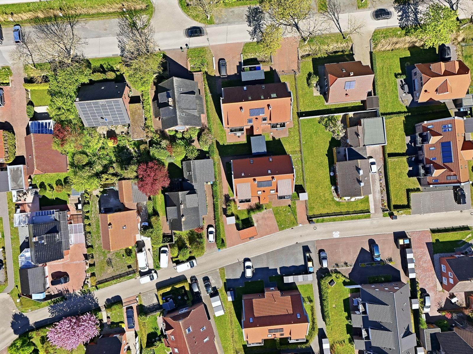 Aerial view of houses with gardens and streets in a quiet neighborhood.