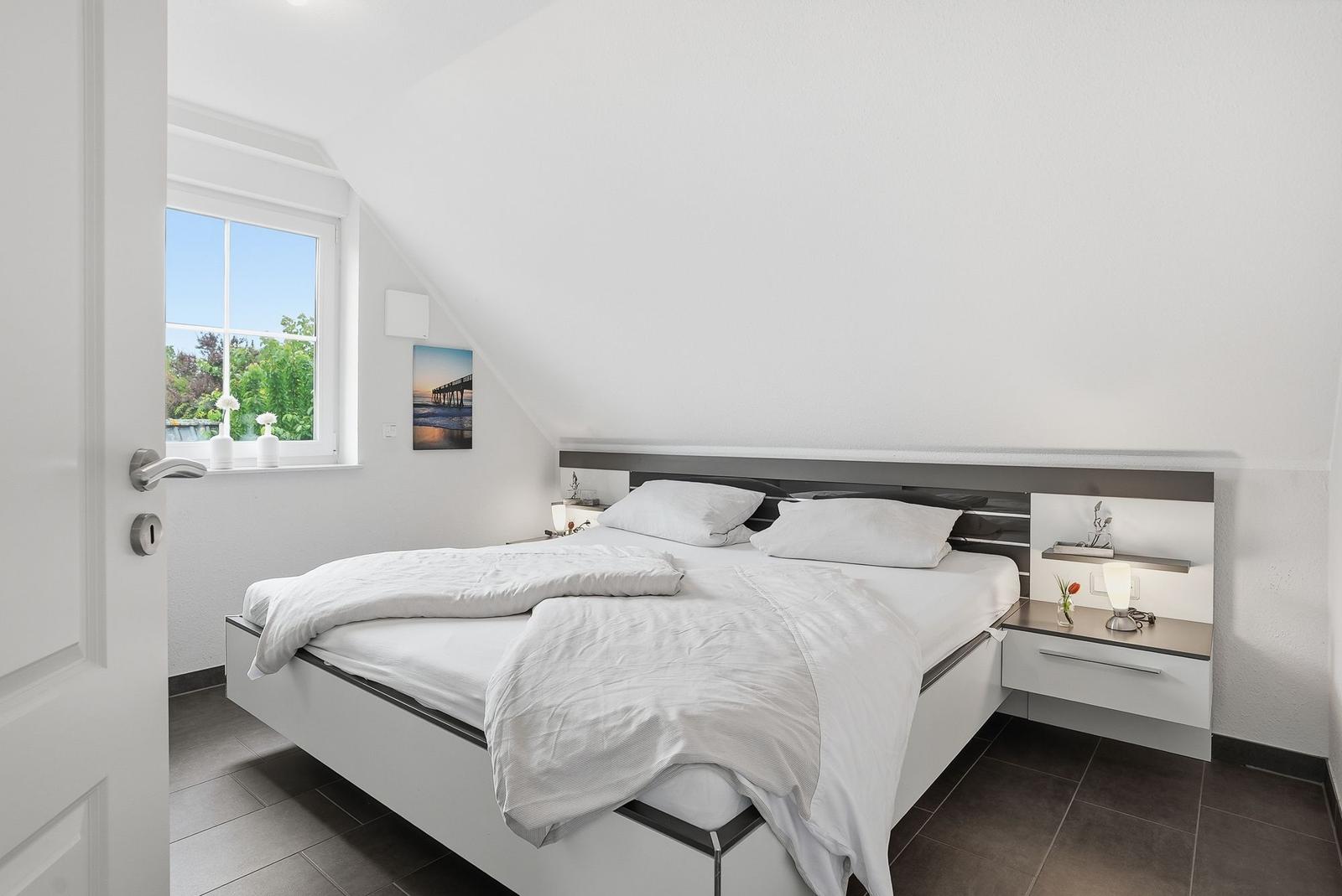 Bedroom with double bed, window, and nightstand.