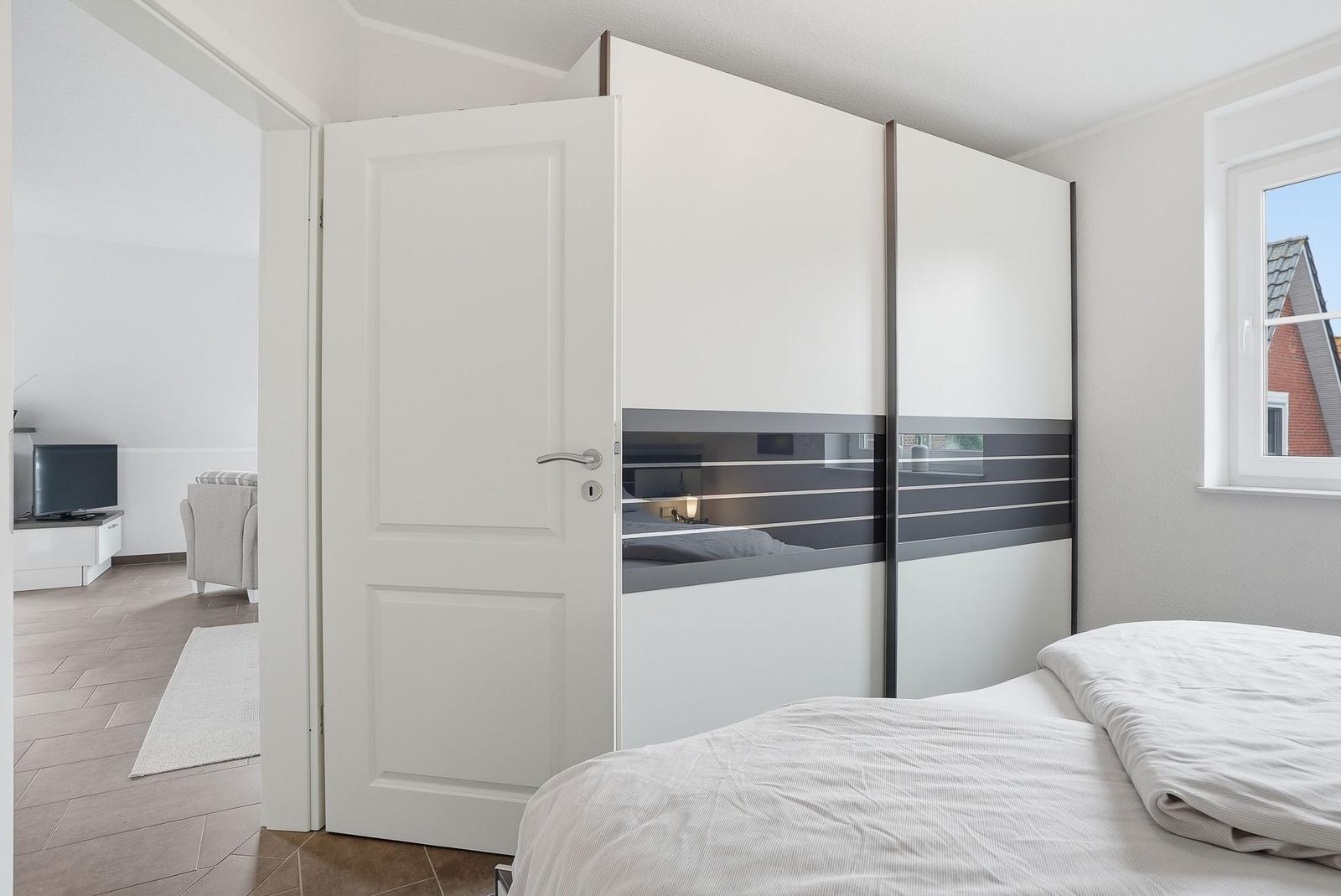 Bedroom with bed, sliding doors, and view into living room.