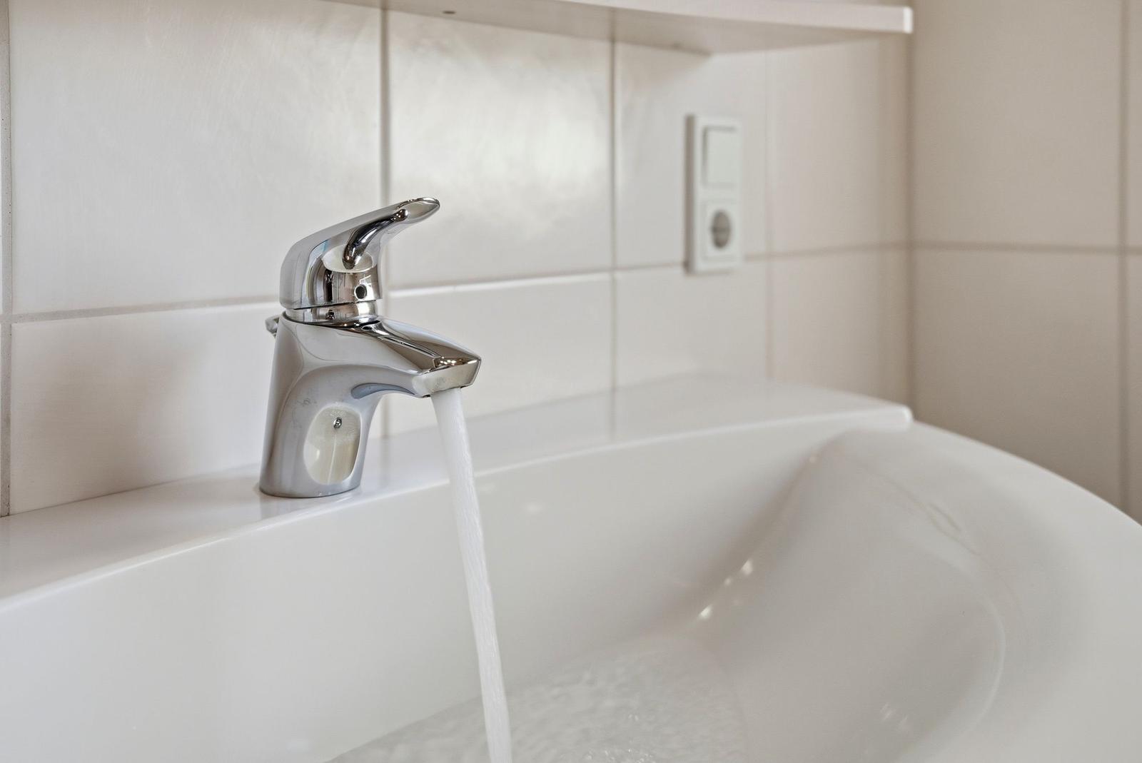 Duschkopf mit Wasserstrahl in weißer Badewanne