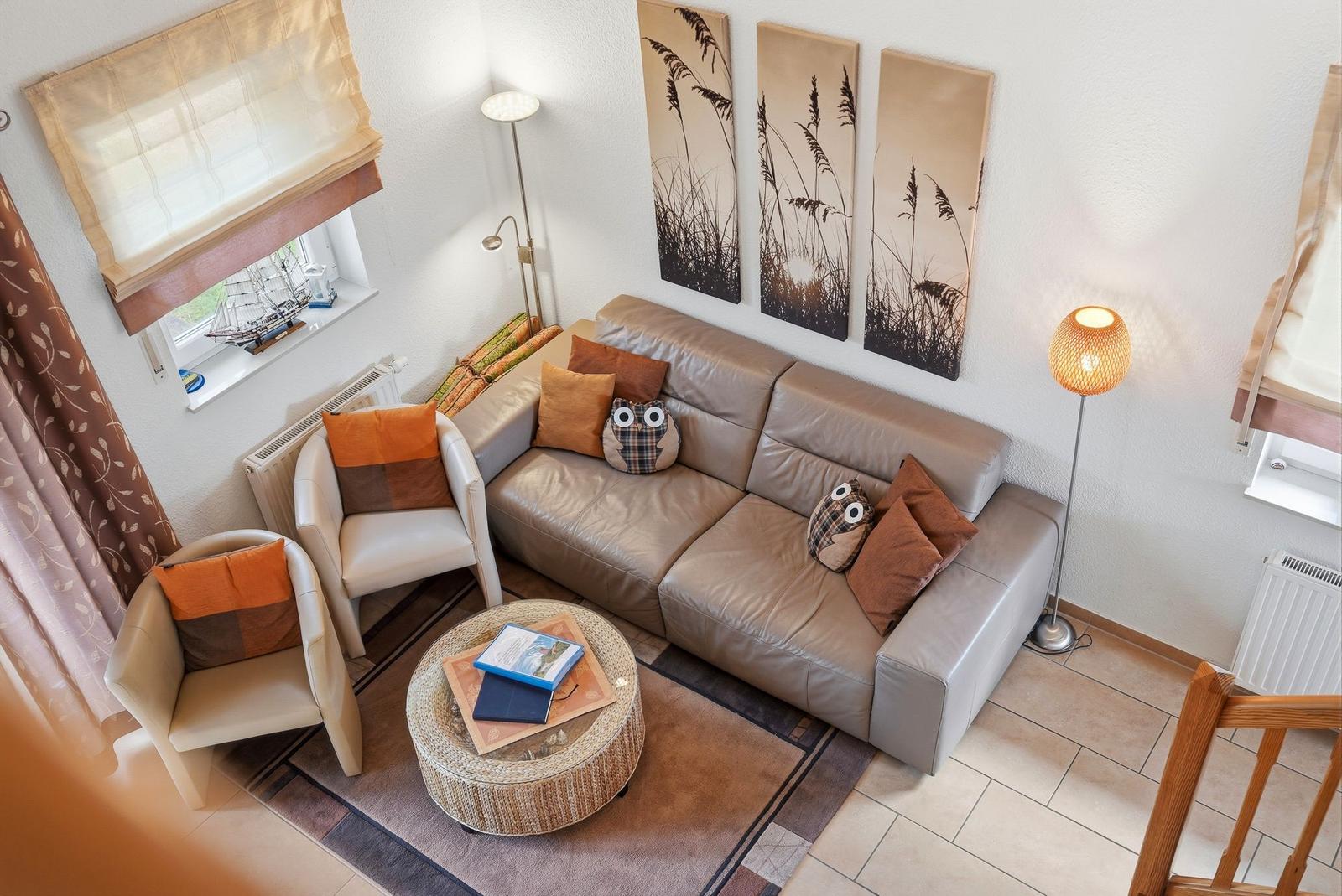 Ein Wohnzimmer mit einem Sofa, zwei Sesseln, einem runden Tisch und Wandbildern.