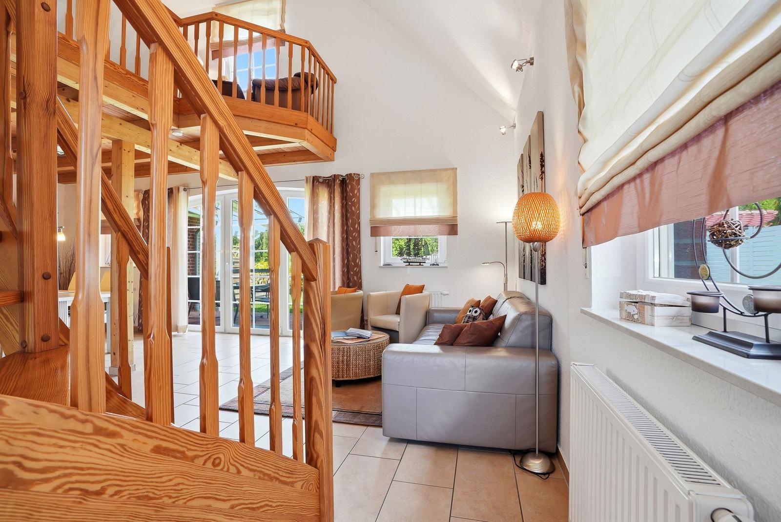 Wohnbereich mit Holztreppe, Sofa und Fenster mit Jalousien.