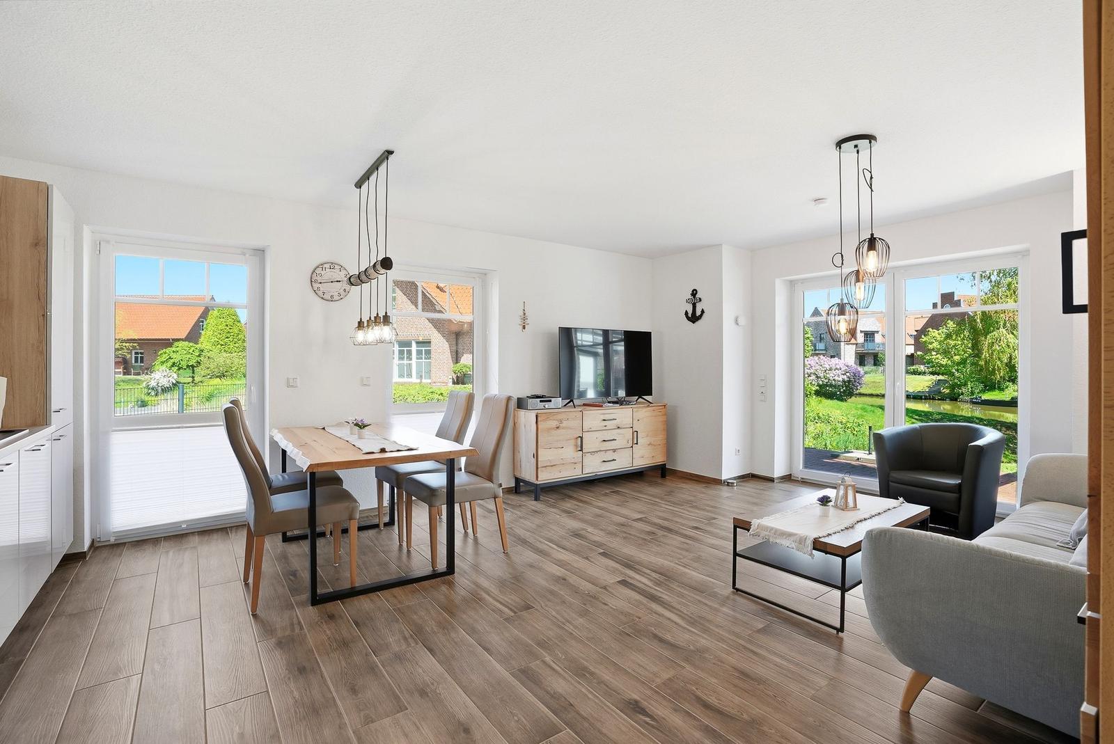 Wohn- und Essbereich mit Holzboden, TV-Schrank und Blick auf einen Kanal.
