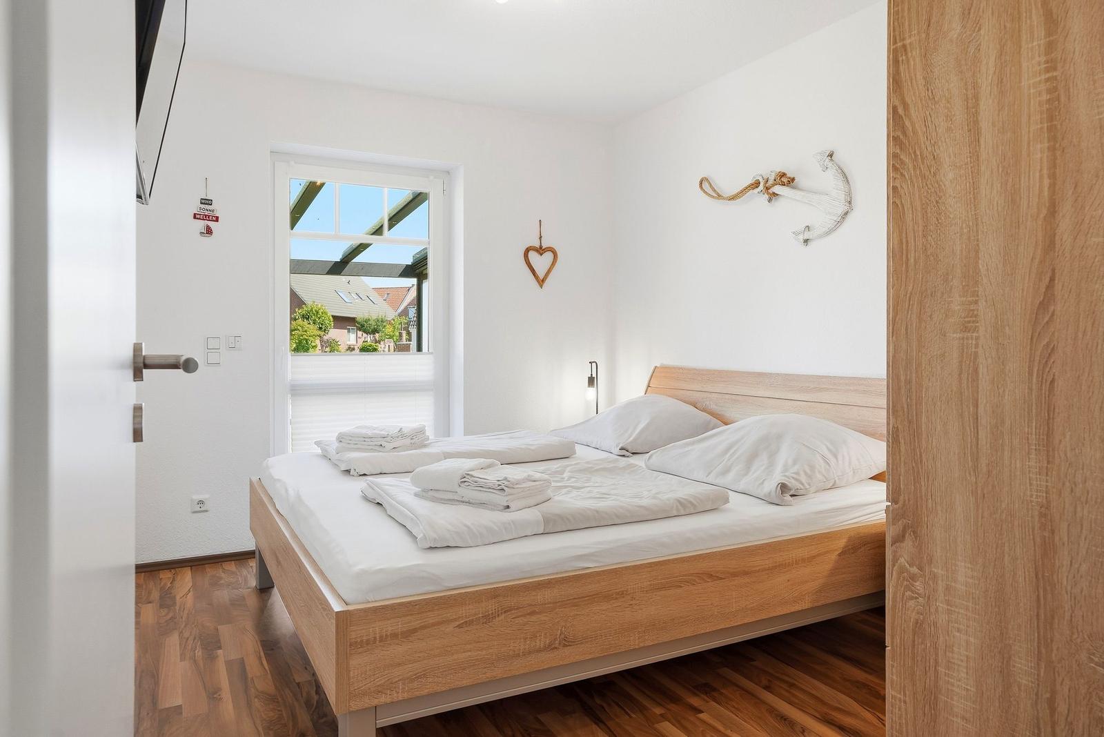 Schlafzimmer mit Holzbett, Fenster und Wanddekoration.