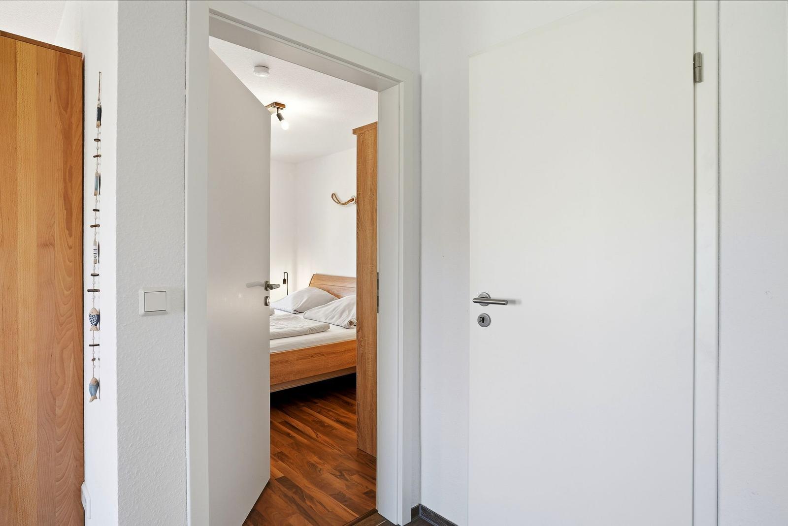 Durchgang zu einem Schlafzimmer mit Holzbett und Parkettboden.