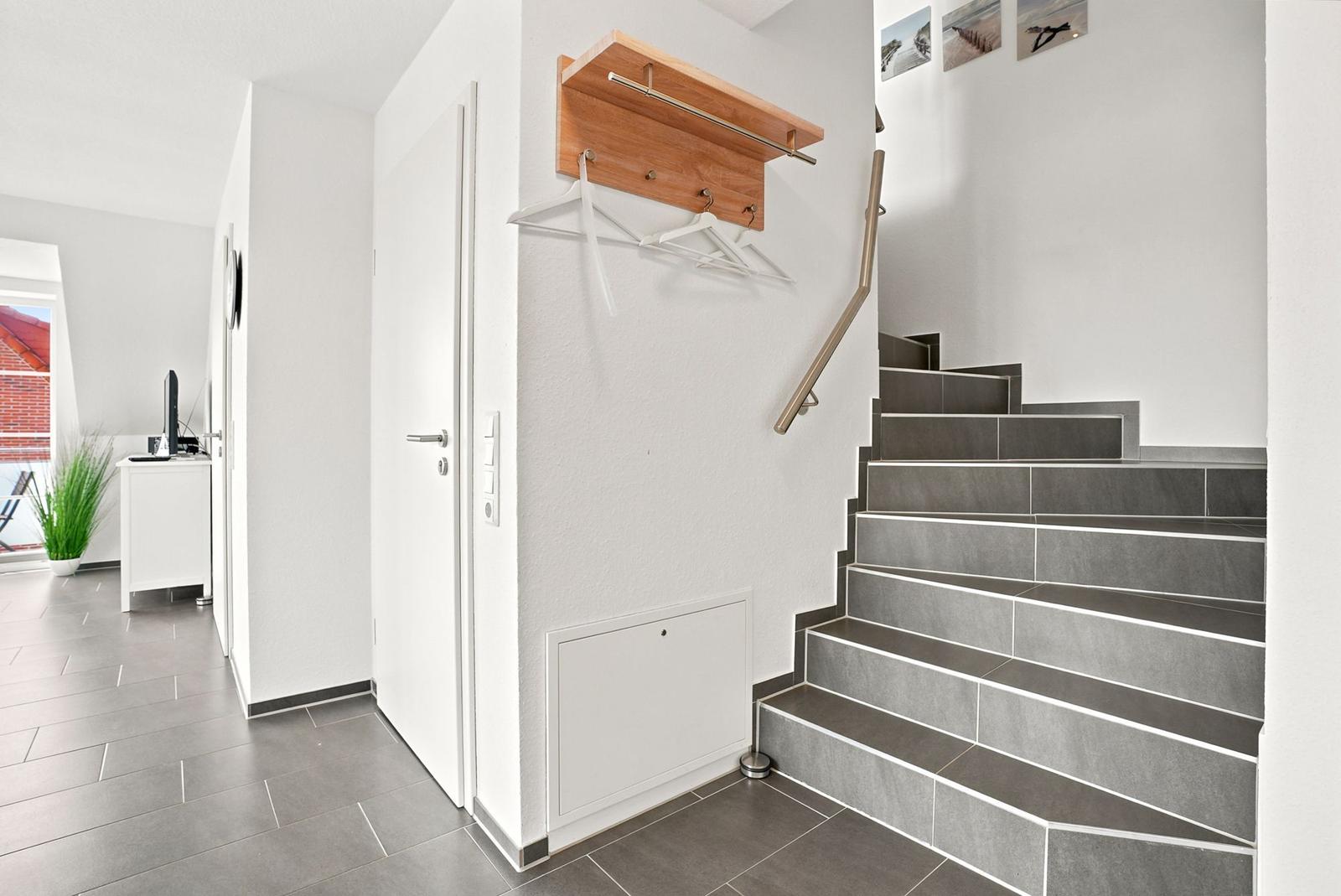 Eingangsbereich mit Treppe, Kleiderhaken und Blick in Wohnbereich.