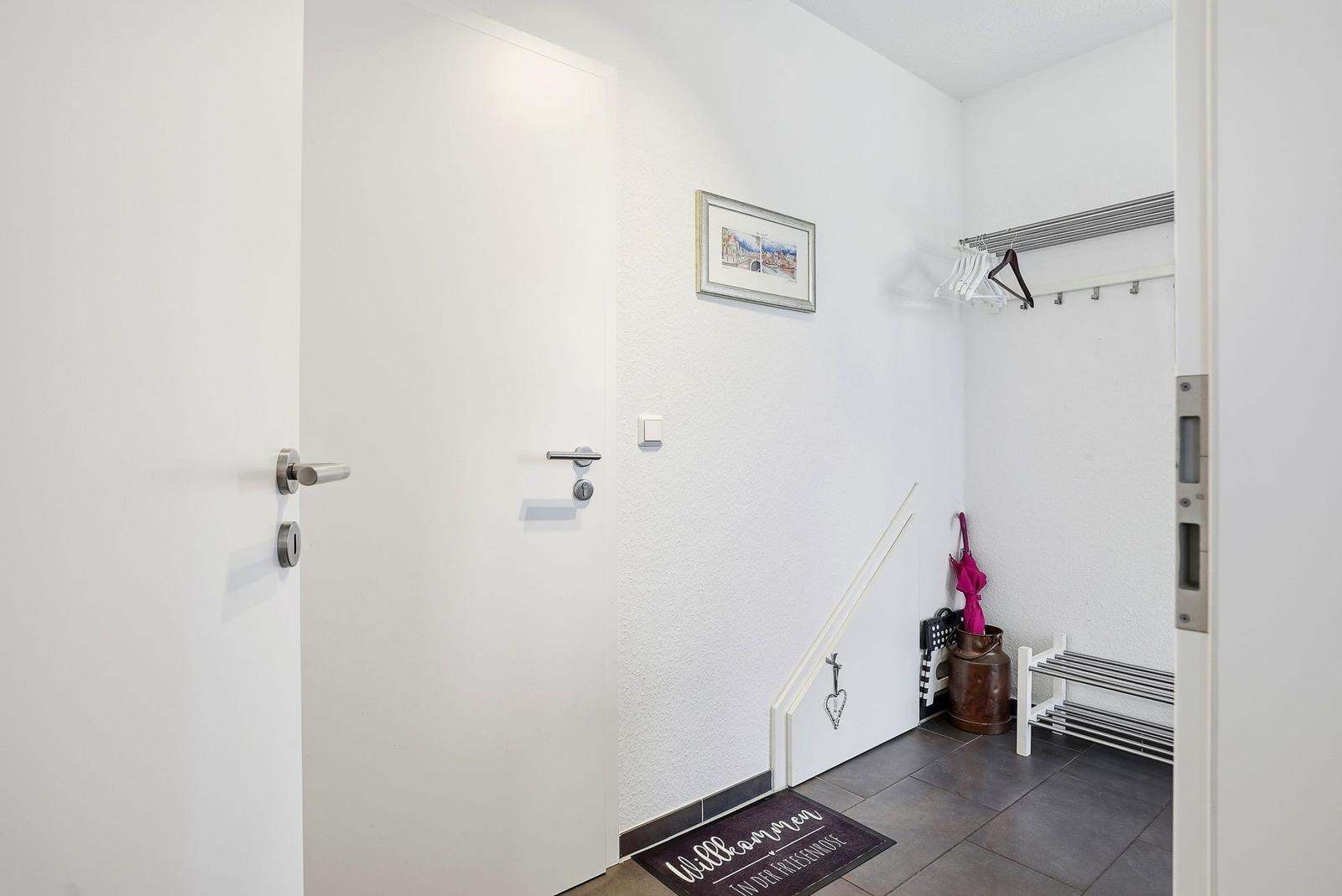 Eingangsbereich mit Garderobe, Begrüßungsmatte und Bild an der Wand.