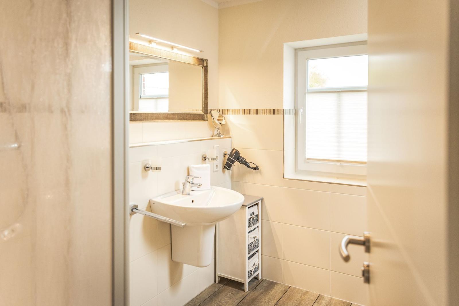 Badezimmer mit Waschbecken, Spiegel und Fenster