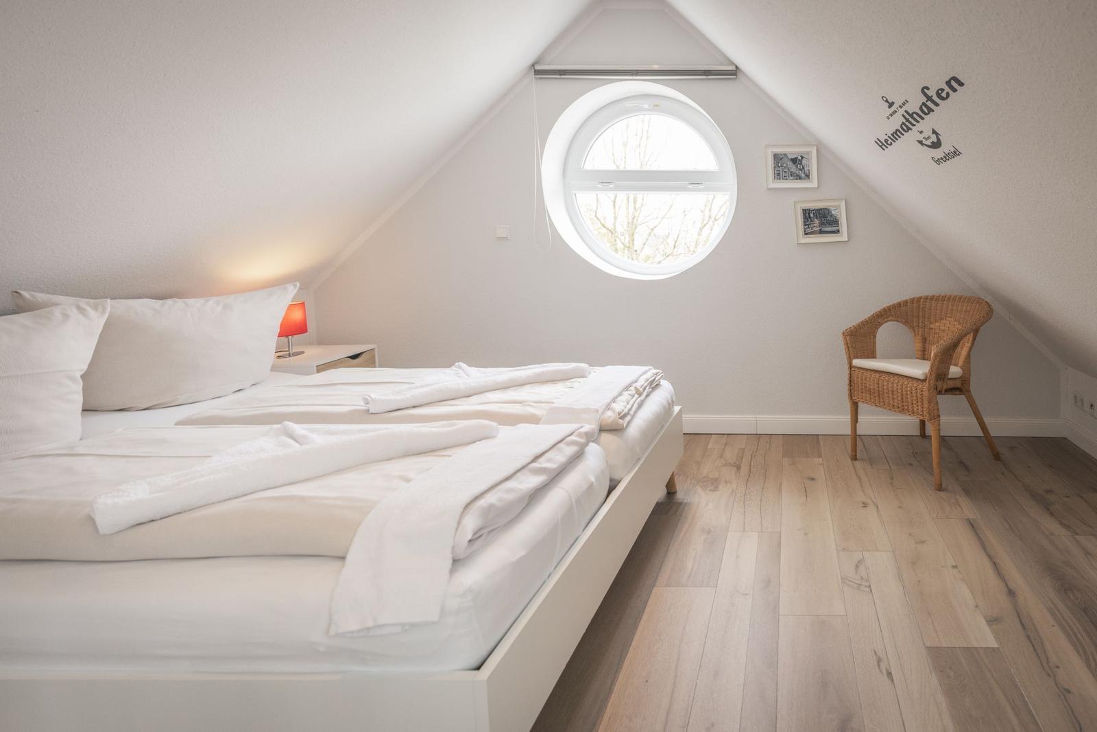 Schlafzimmer mit Dachfenster, Bett und Stuhl.