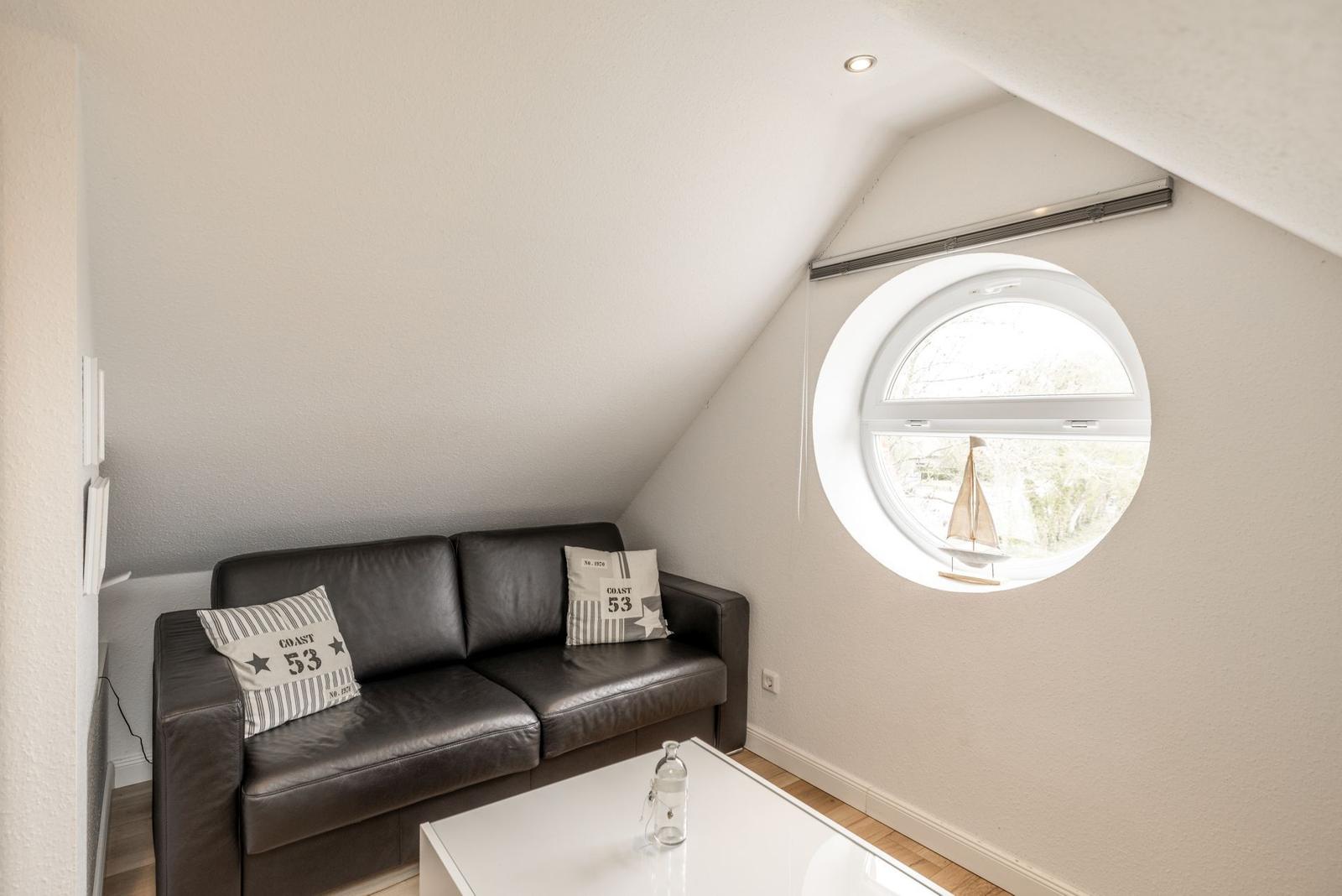 Schlafzimmer mit Sofa, runden Fenster und Tisch