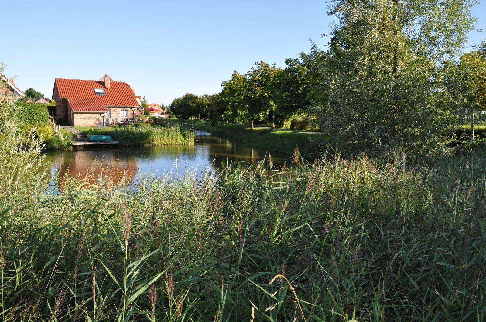Haus am Kanal mit Gras und Bäumen