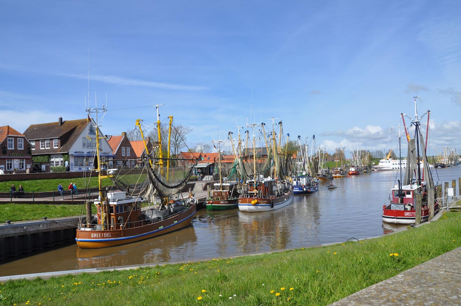 Hafen mit mehreren Fischereischiffen und traditionellen Häusern am Ufer.