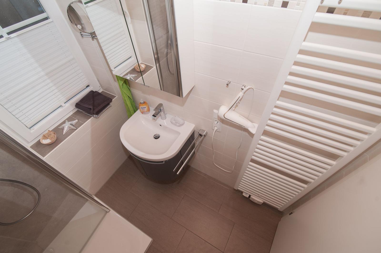 Badezimmer mit Dusche, Waschbecken und Heizkörper