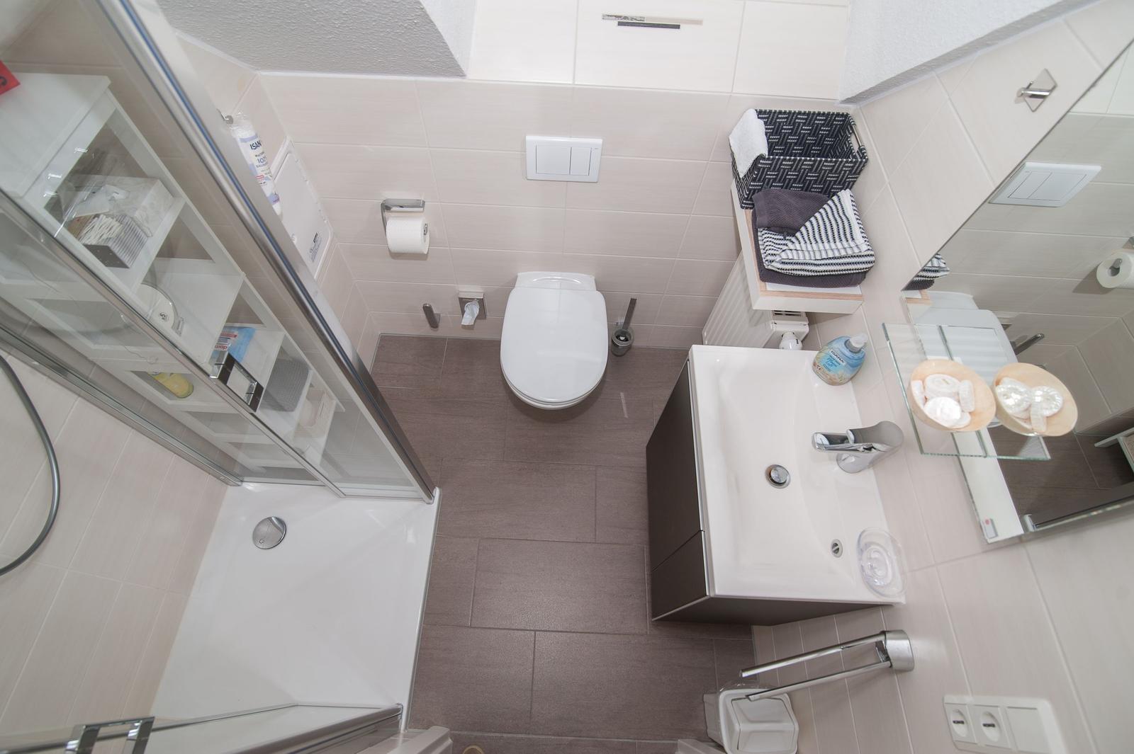 Badezimmer mit Dusche, Toilette und Waschbecken.