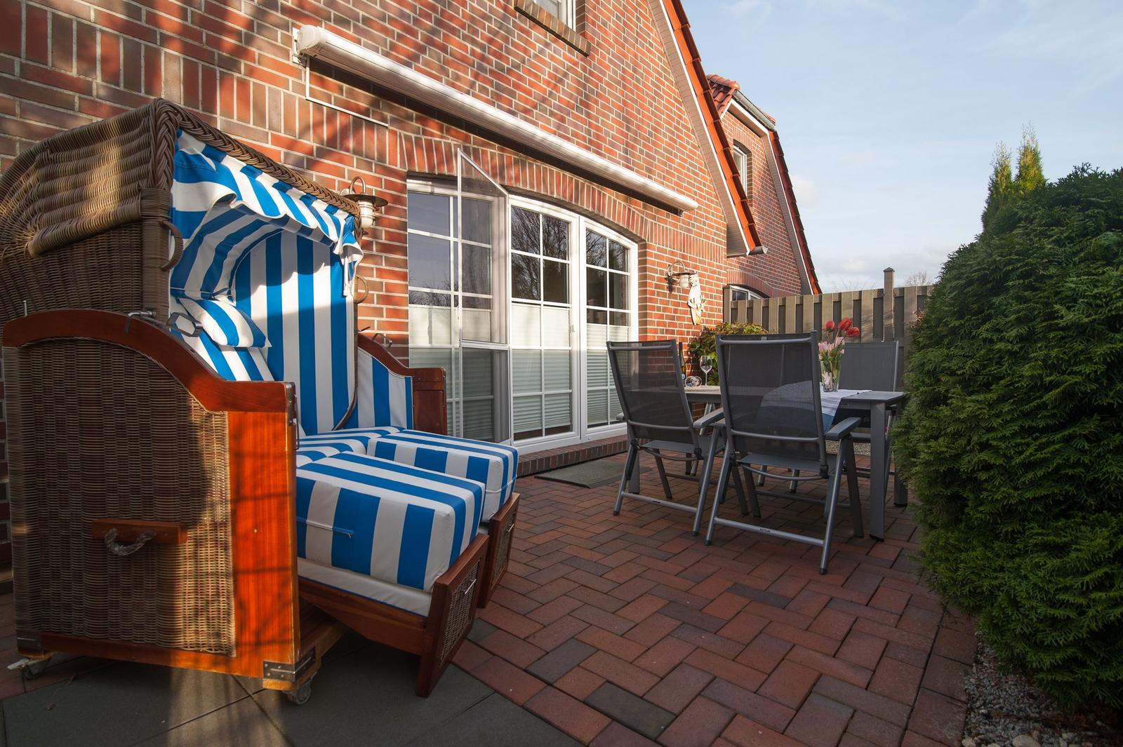 Terrasse mit Strandkorb, Tisch und Stühlen vor Backsteinhaus