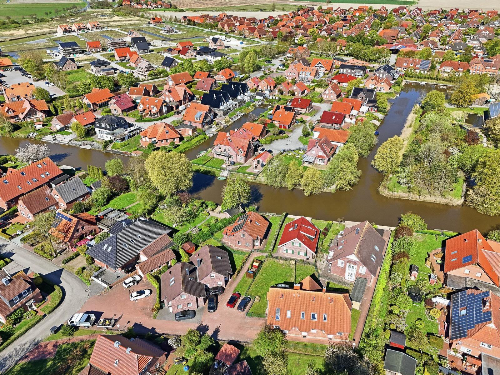 Luftbild eines Dorfes mit Häusern, Kanälen und Grünflächen.