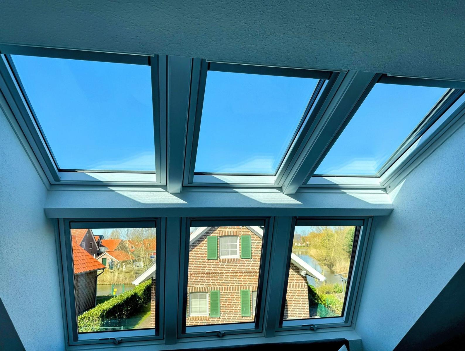 Dachfenster und Fenster zeigen Blick auf Häuser und Fluss.