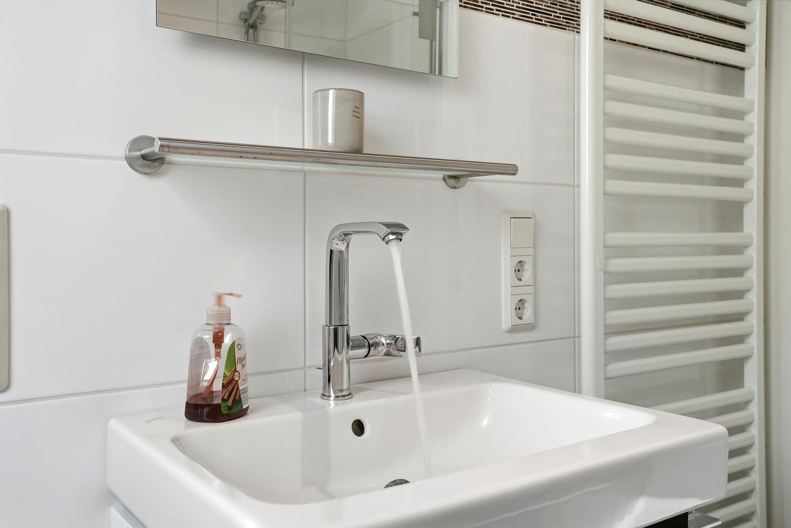 Waschbecken mit laufendem Wasser, Spiegelschrank und Handtuchhalter