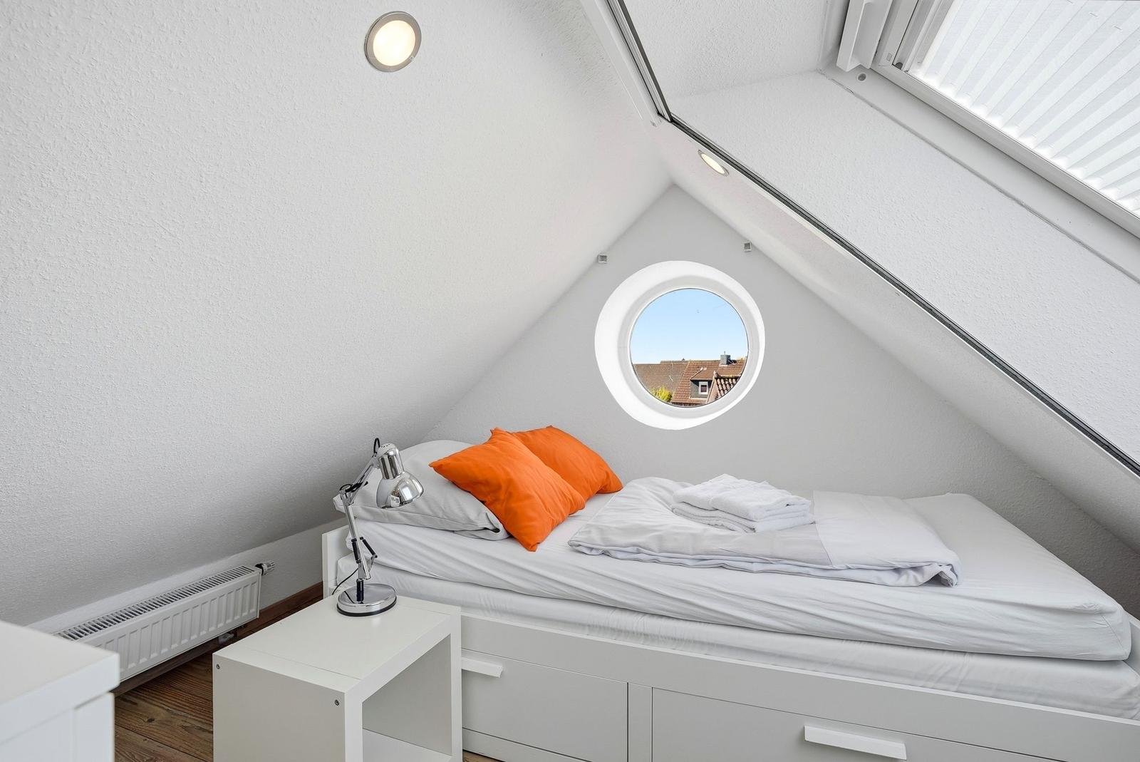 Schlafzimmer mit Dachfenster, Bett und Nachttisch