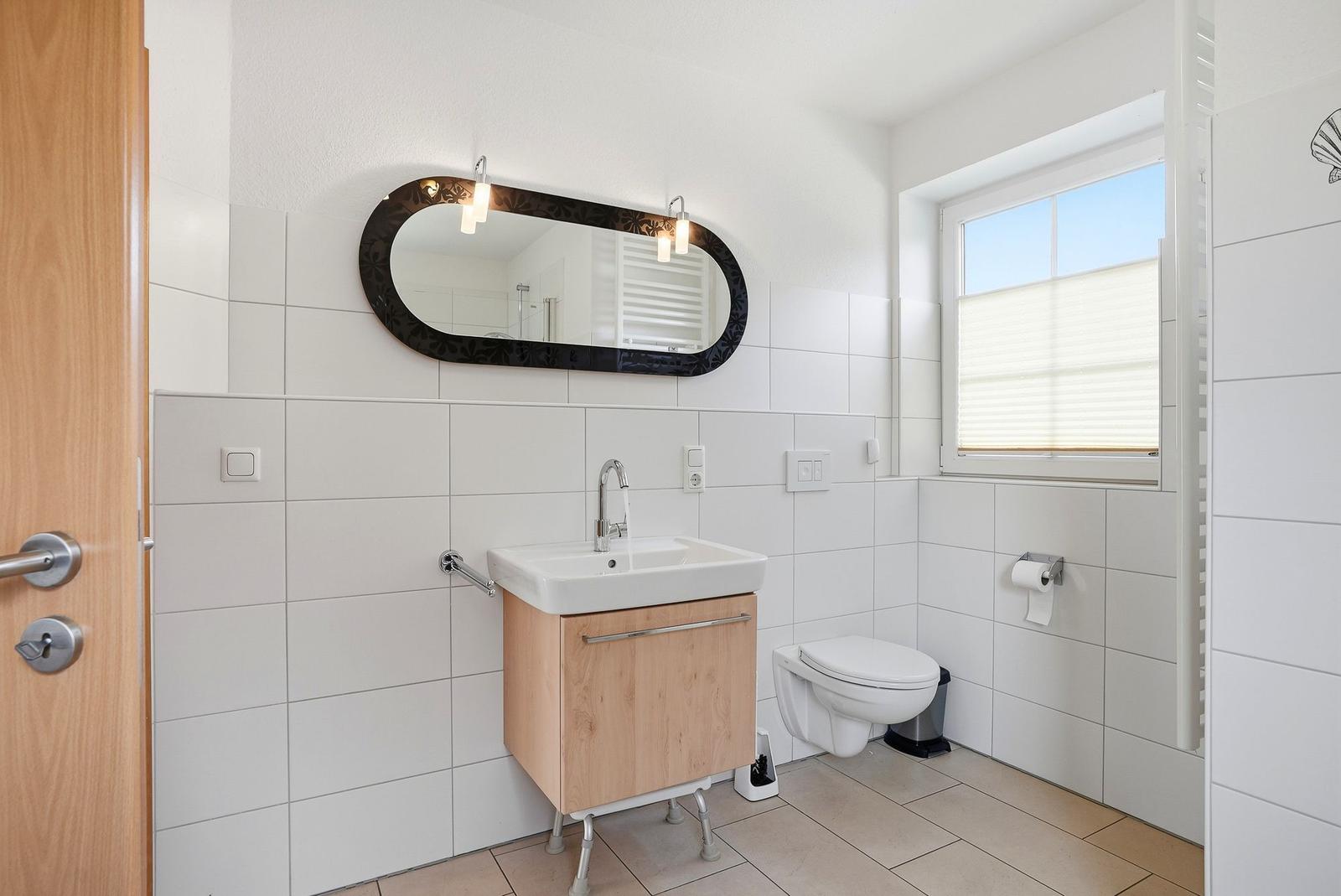 Badezimmer mit Waschbecken, Toilette und Spiegel an der Wand.