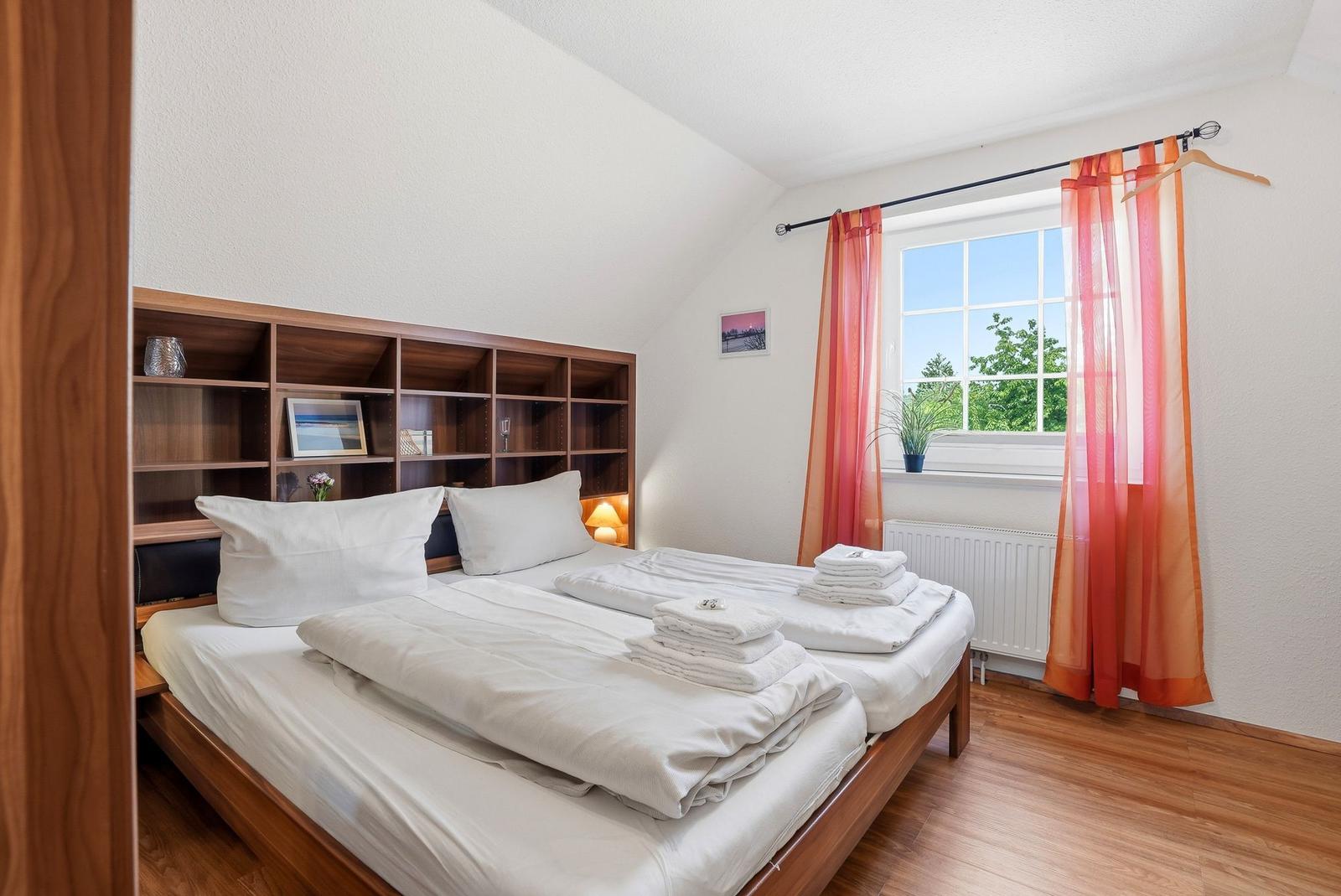 Schlafzimmer mit Doppelbett, Holzmöbel und Fenster mit Blick auf Grün.
