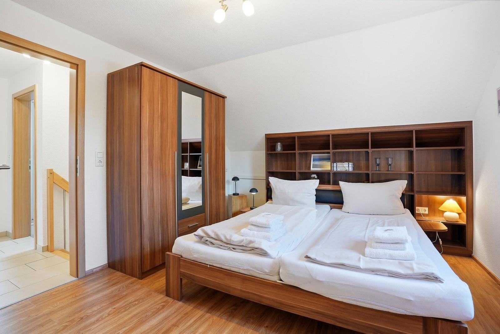 Schlafzimmer mit Doppelbett, Holzmöbel und integriertem Regal