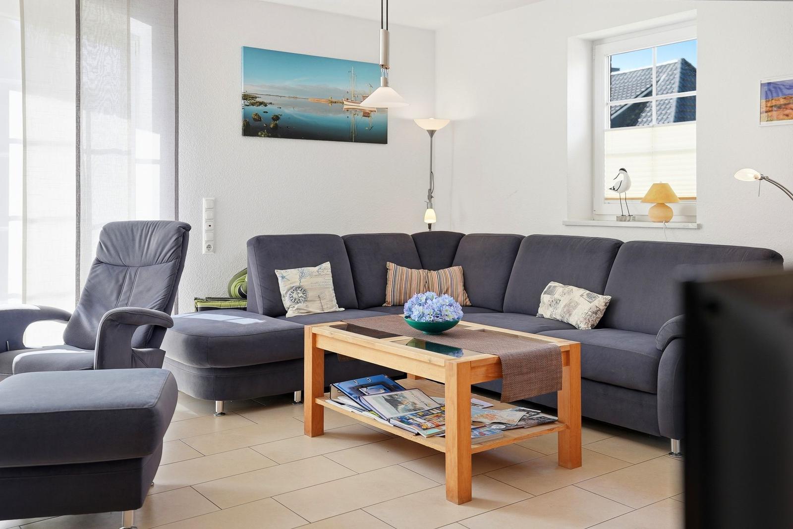 Ein Wohnzimmer mit grauem Sofa, Holztisch und Wandbild.