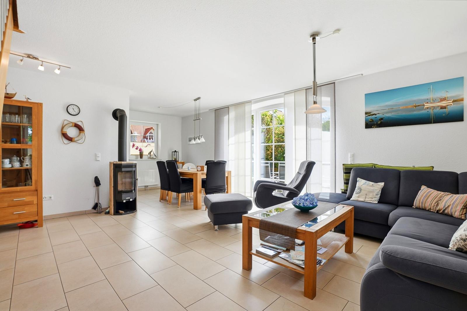 Wohn- und Essbereich mit Sofa, Esstisch und Kaminofen.