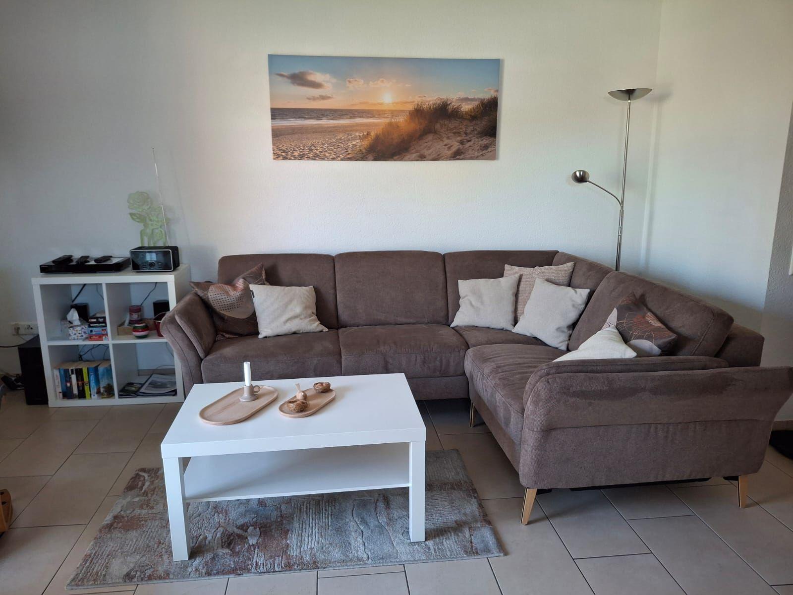 Ein Wohnzimmer mit braunem Sofa, weißem Couchtisch und Wandbild