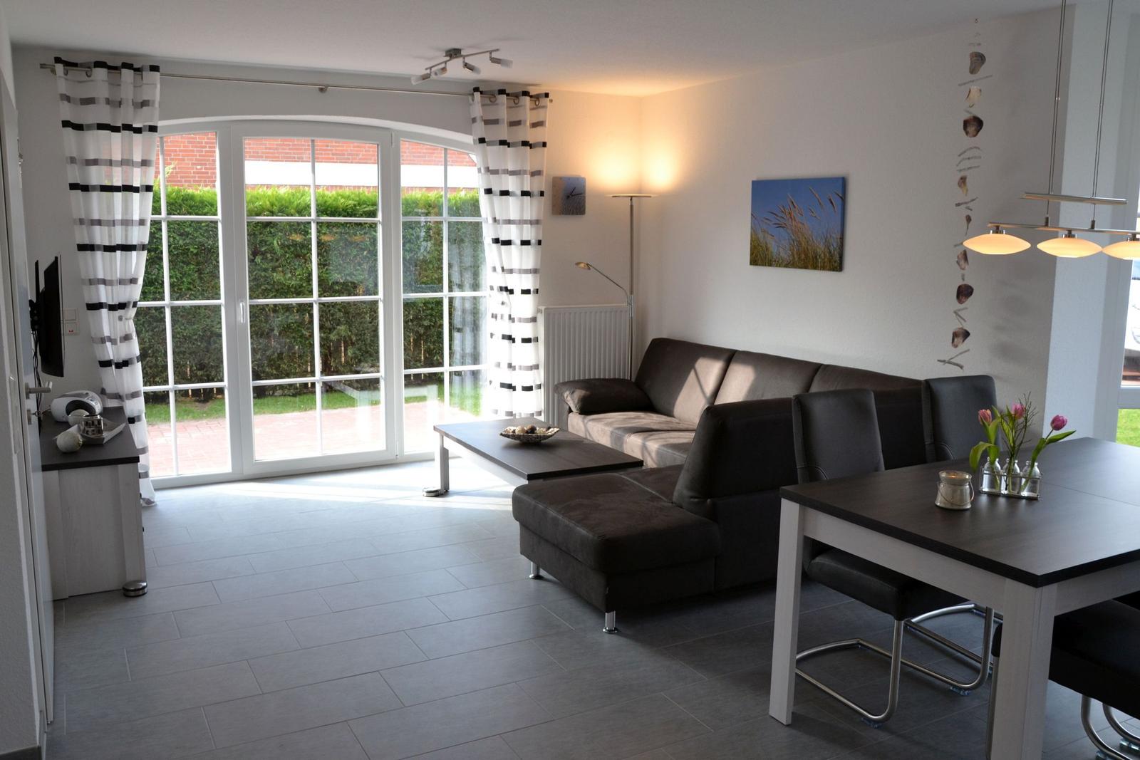 Wohn- und Essbereich mit Sofa, Tisch und Blick auf den Garten.