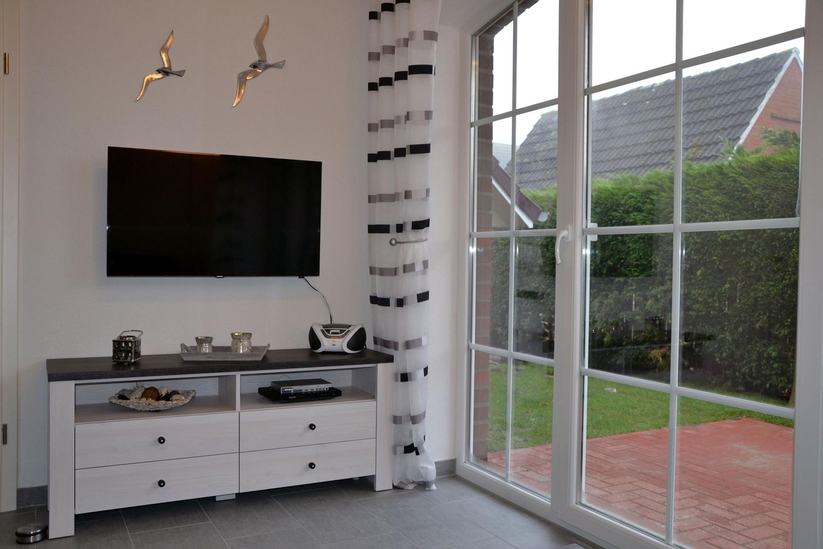 TV auf Wandhalterung über Schrank mit Fenster zum Garten