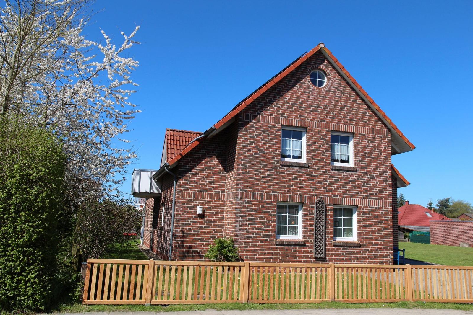 Red brick house with wooden fence and blue sky